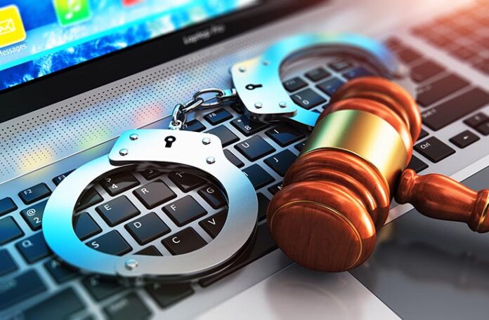 Handcuffs and a judge gavel on a laptop keyboard illustrating that piracy is not legal