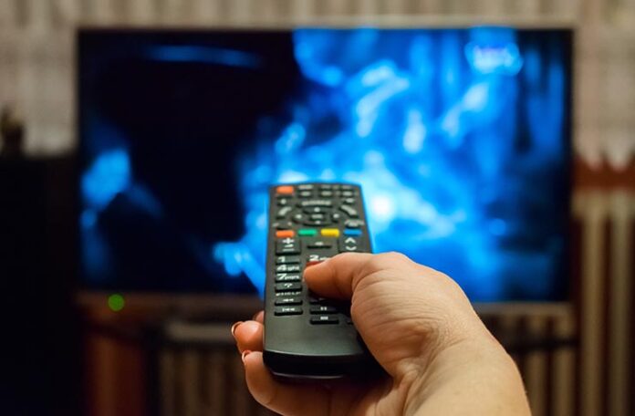 A hand pointing a remote at TV to access streaming services.