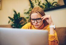confused woman with glasses staring at laptop screen