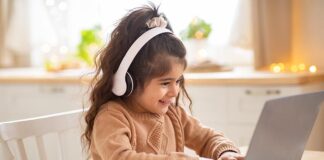 Young girl with headphones using laptop