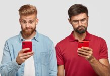 Two adult males viewing mobile phone screens with confused looks.