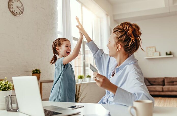 young girl and mother high five in front of laptop