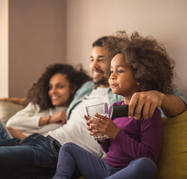 Young family with child watching TV on sofa