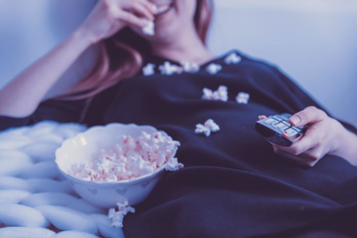 Woman on a couch eating popcorn