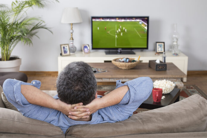 Man relaxing on the couch while watching the Champions League Final soccer match on TV