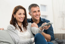 Smiling couple sitting together on the couch while streaming TV.
