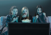 Three scared teenage girls streaming a horror movie on TV