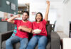 Young couple celebrating while watching college football on TV at home