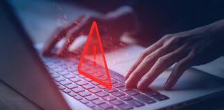Hands typing on a laptop with an icon of a warning label depicting illegal activities.