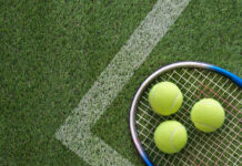 How To Watch Wimbledon Three tennis balls and a tennis racket lying on a grass tennis court