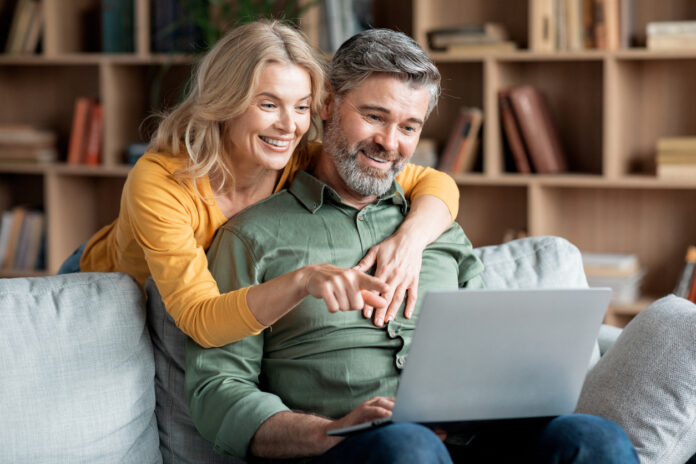 Middle aged couple smiling while safely browsing the Internet on a laptop