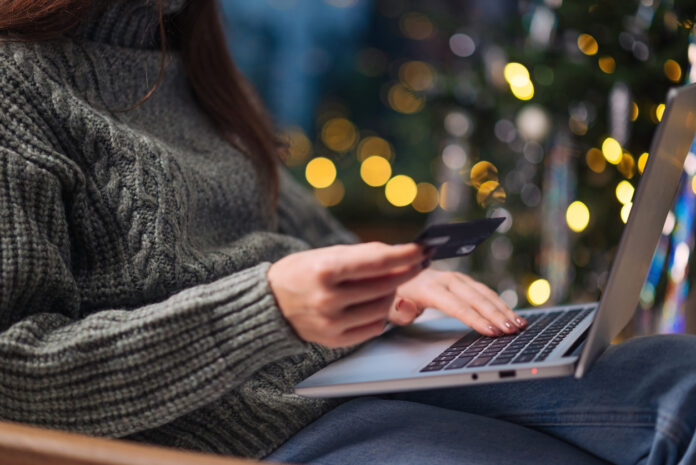 Female hands on the laptop with credit card and blurred bokeh lights