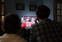 Behind the Curtain: How Illegal Sports Streaming Sites Work A father and a child watching a football game on tv