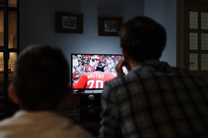 A father and a child watching a football game on tv