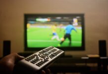 Illegal Sports Streaming Stats You Need To Know A person's hand holding a remote control