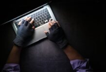 How to Report a Scam Website A Person Typing on Laptop while Wearing a Fingerless Gloves