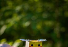 A Minecraft Movie A hand holds a paper craft bee figure similar to a minecraft figure