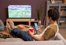 How to Safely Watch the 2026-27 NFL Regular Seasonย Back view at young man watching football game at home and relaxing on couch with mobile streaming